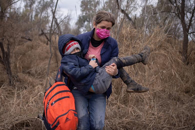 Gabriella, una migrante hondureña en busca de asilo, carga a su hijo Diego de seis años mientras caminan por la maleza después de cruzar el río Grande hacia los Estados Unidos desde México.