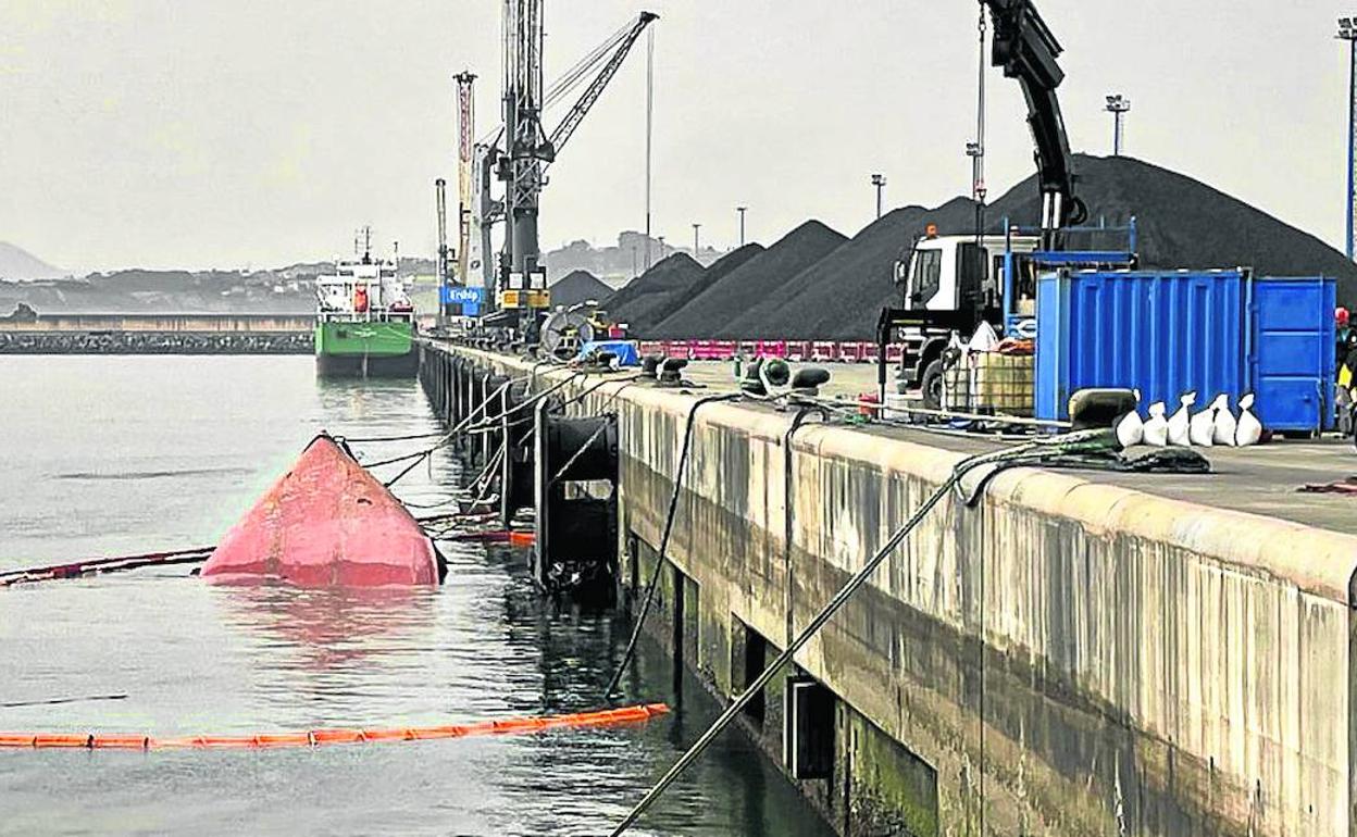 La proa del 'Nehir', ayer, apenas visible en el muelle Norte de la ampliación y rodeada de barreras flotantes.