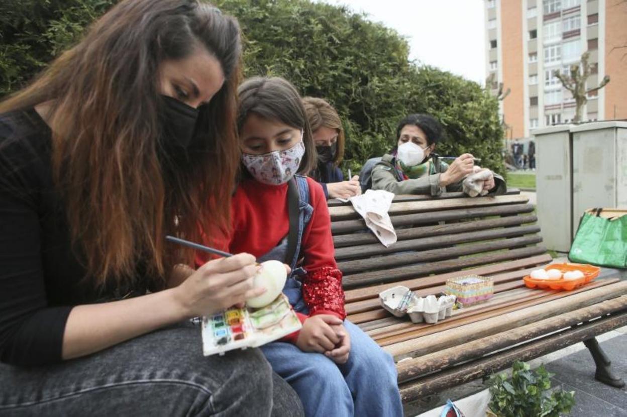 Las artesanas Ana Domínguez; María Cimadevilla y Bárbara Méndez, acompañada de su hija Carla, pintan güevos pintos en un parque poleso. 