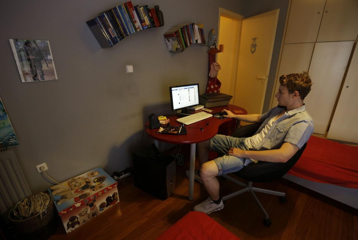 Un joven, delante del ordenador, en su habitación de la casa familiar. 