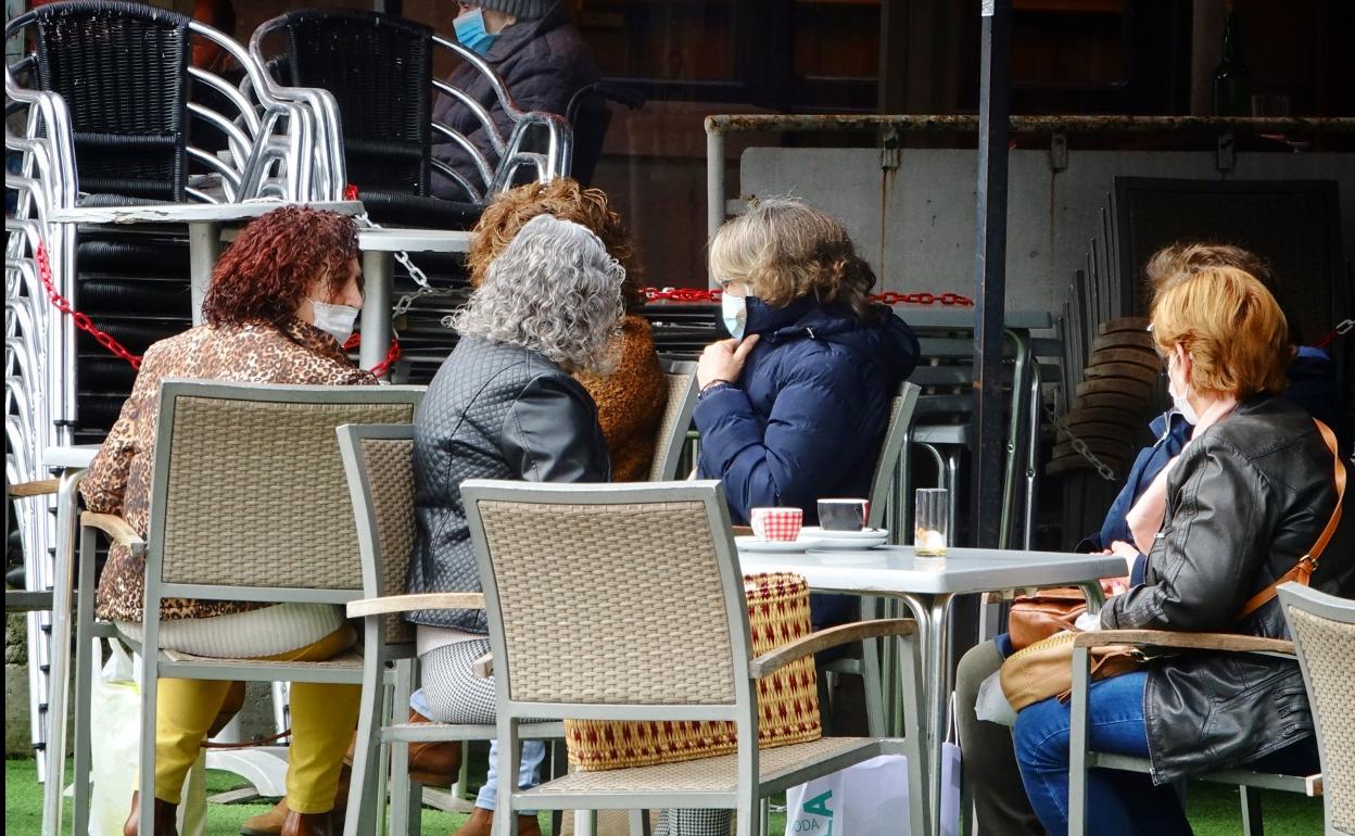 Varias personas toman algo en una terraza de Llanes. 
