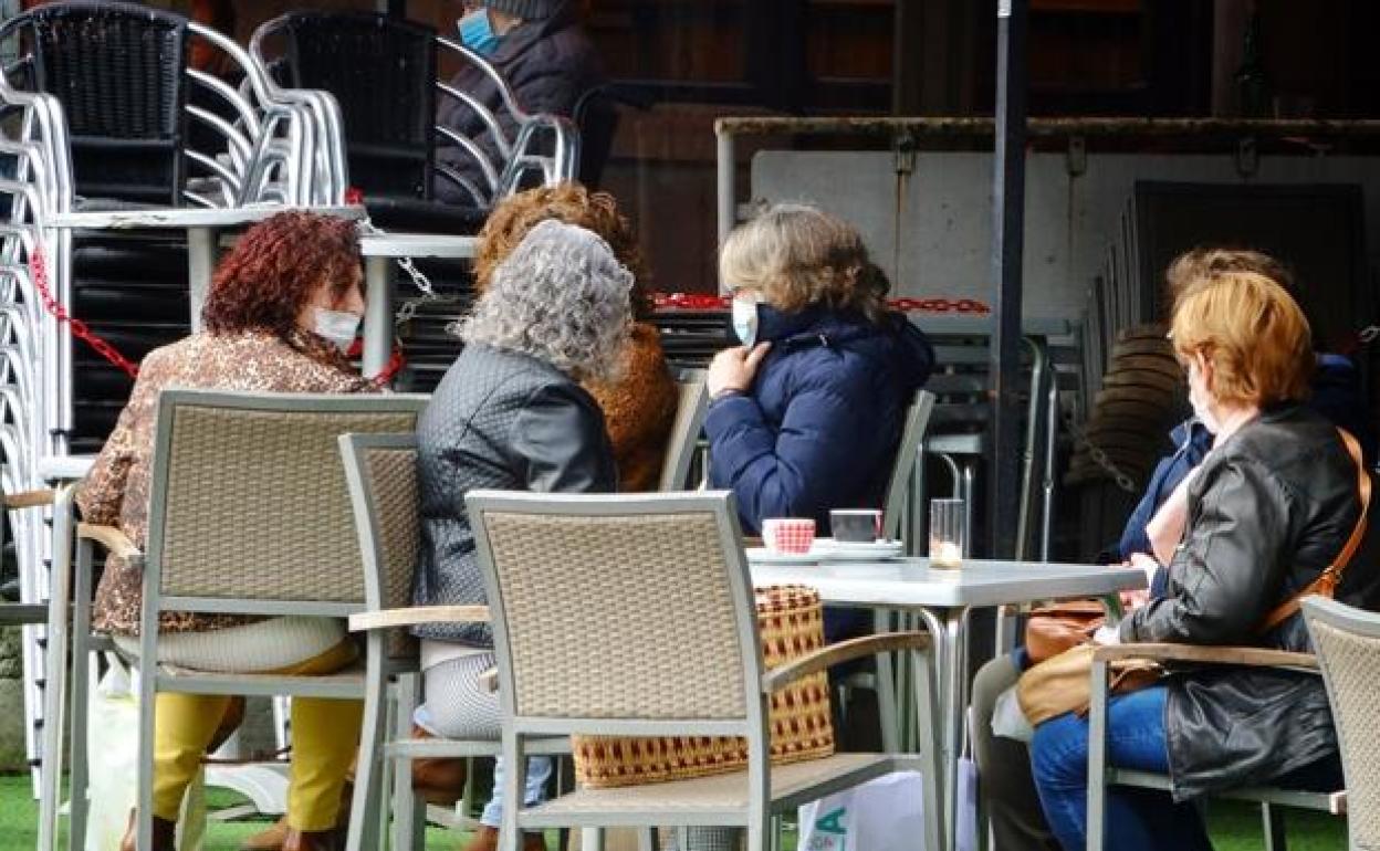 Varias personas toman algo en una terraza de Llanes.