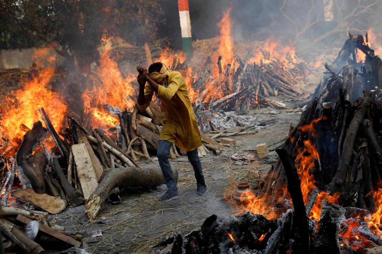 Un hombre pasa corriendo junto a las piras funerarias de víctimas de coronavirus en Nueva Delhi. 