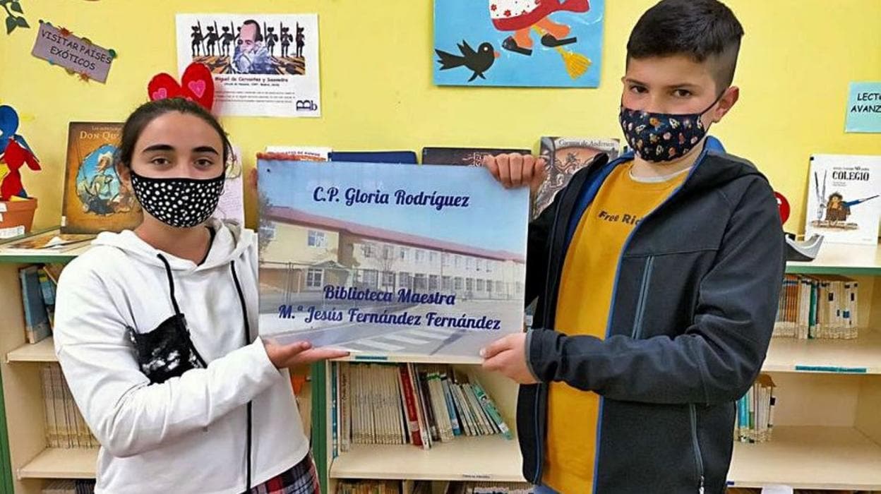 Dos alumnos con la placa que lleva el nombre de la maestra fallecida. 