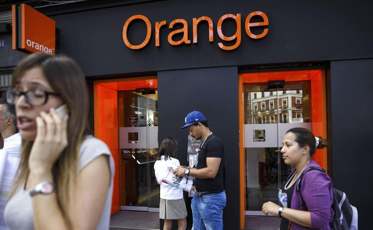 Un grupo de personas delante de una tienda Orange.