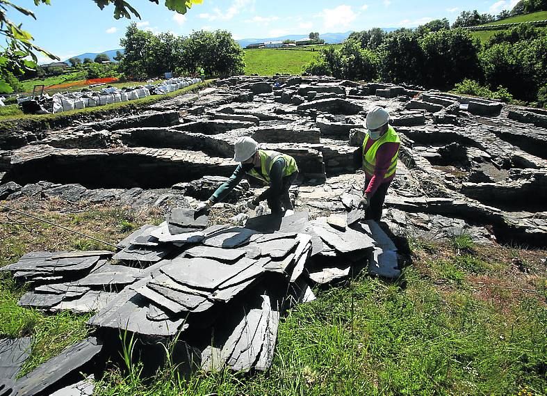 Los operarios se afanan en la retirada de la gravilla sobre la malla geotextil y de la pizarra, mientras se apuran las labores de documentación previas a las obras de restauración.