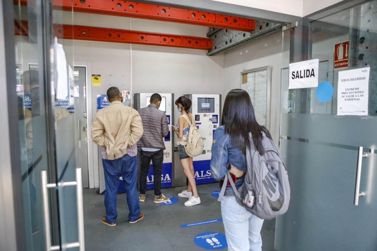 Una joven ayuda a dos hombres a sacarse el billete. 