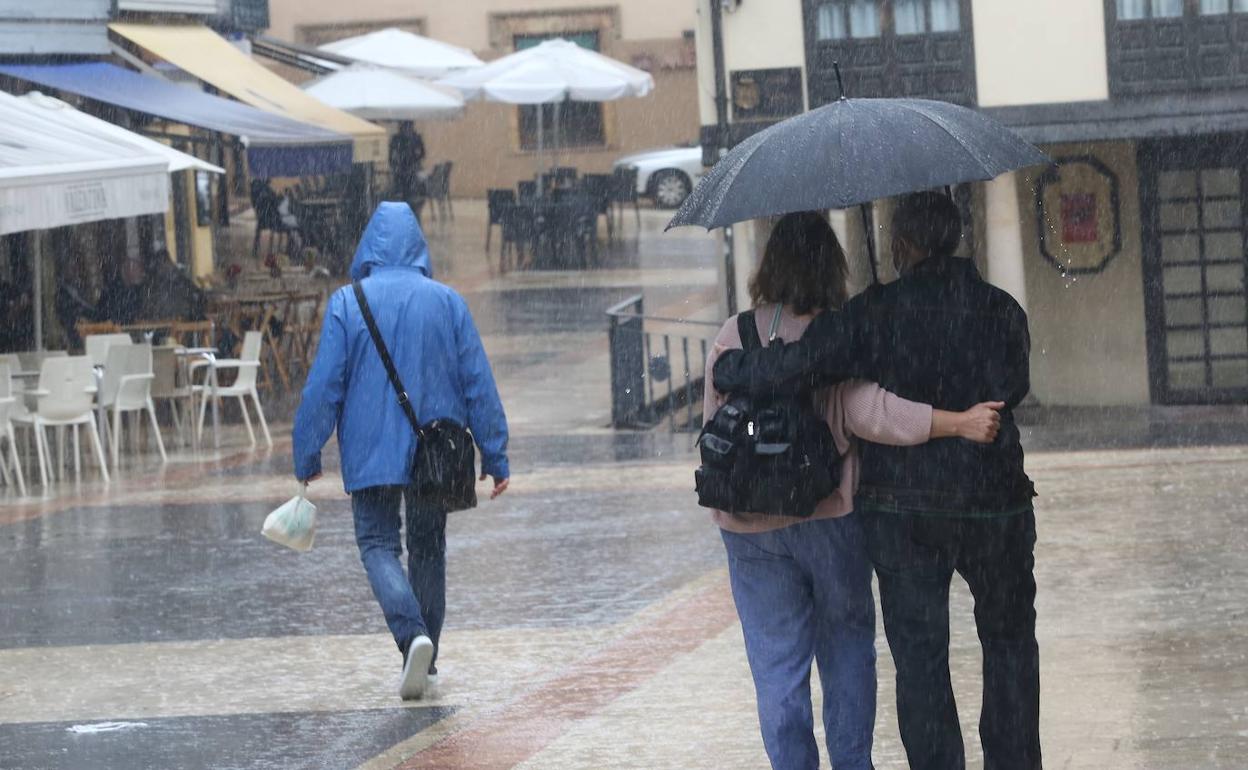 Una pareja camina por el centro de Oviedo bajo la lluvia.