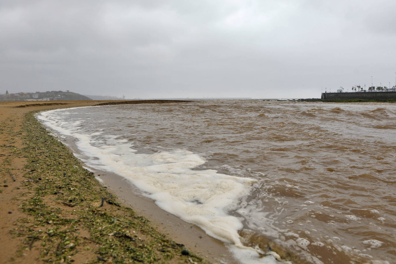 Gijón cierra al baño el tramo entre las escaleras 12 y 15 de la playa de San Lorenzo por los alivios al río Piles provocados por el temporal de lluvias. 