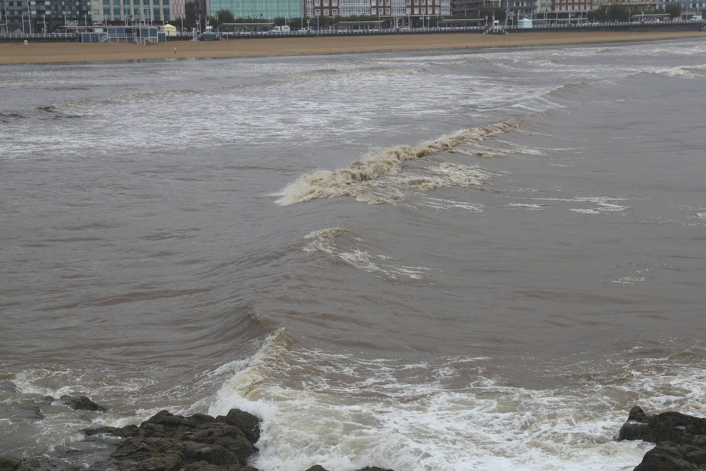 Gijón cierra al baño el tramo entre las escaleras 12 y 15 de la playa de San Lorenzo por los alivios al río Piles provocados por el temporal de lluvias. 