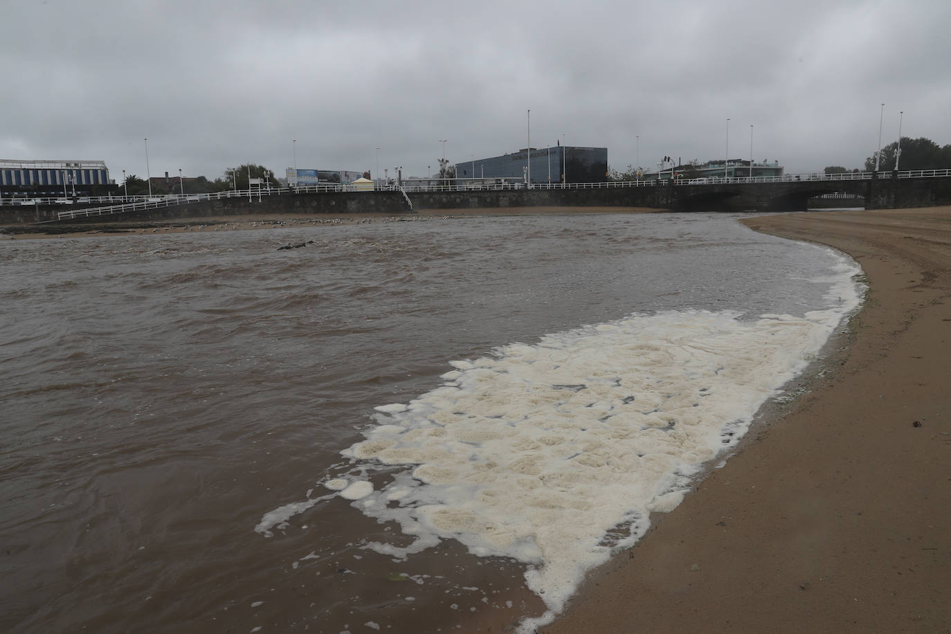 Gijón cierra al baño el tramo entre las escaleras 12 y 15 de la playa de San Lorenzo por los alivios al río Piles provocados por el temporal de lluvias. 