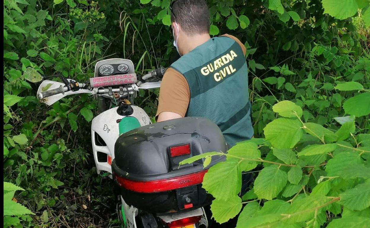 Un agente con la moto recuperada entre matorrales, en La Franca. 