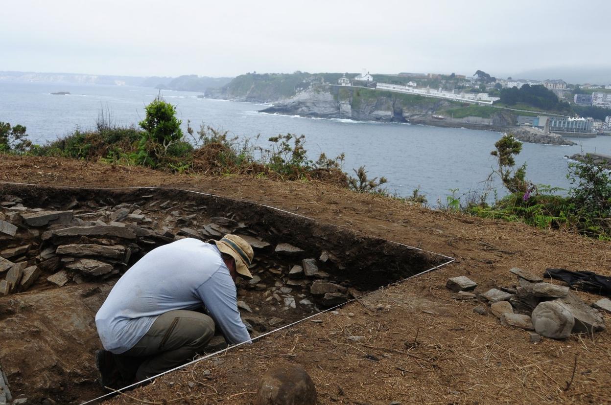 El arqueólogo Valentín Álvarez, durante uno de los sondeos del castrode Castiel con la villa de Luarca al fondo. 