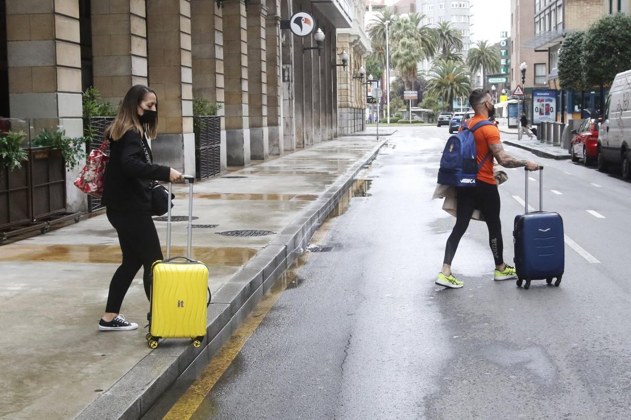 Una pareja de turistas cruza con sus maletas la gijonesa calle de Marqués de San Esteban en dirección al hotel donde están alojados. 