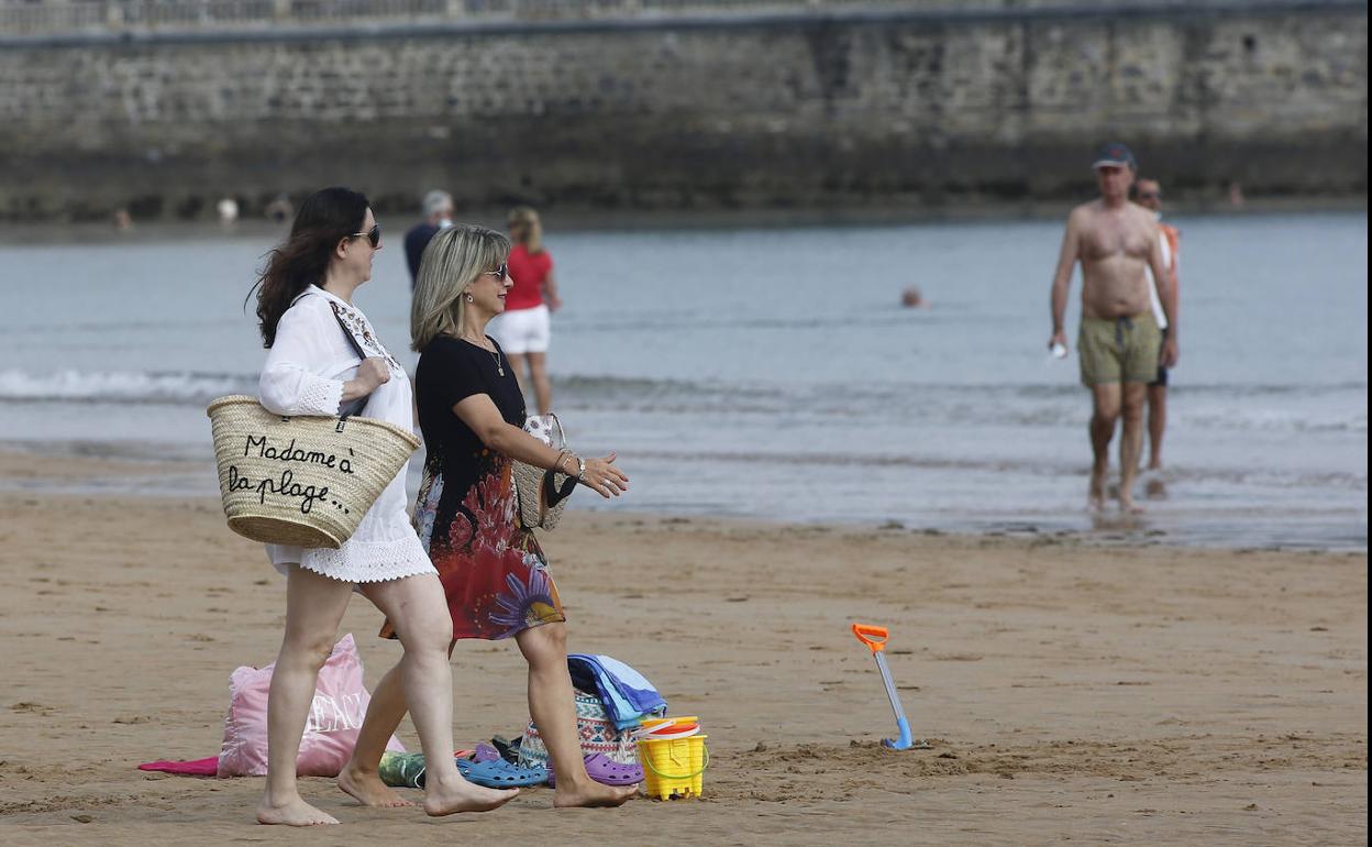 Varias personas pasean este domingo por la playa gijonesa de San Lorenzo 