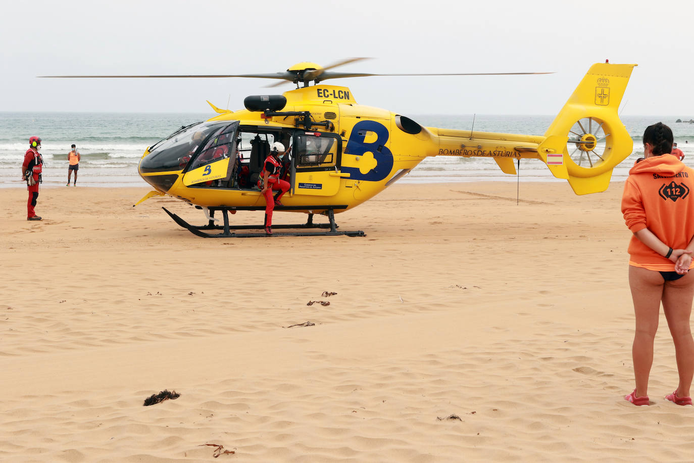 El helicóptero del Servicio de Emergencias del Principado realizó esta mañana un simulacro en la playa de Rodiles. La actuación, que contaba con la participación de más de veinte profesionales, despertó la curiosidad entre los bañistas. El objetivo de este simulacro es enseñar a los socorristas cómo actuar en caso de emergencia durante este verano. El equipo rescatador explicó cuál es la mejor zona para el aterrizaje y cómo deben prepararse.