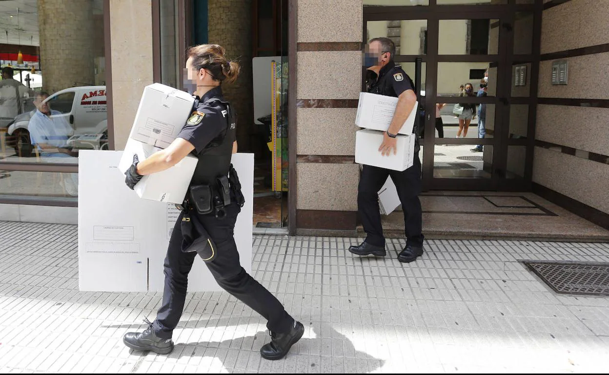 Agentes de la Policía Nacional sacan cajas de pruebas del lugar en el que ocurrieron los hechos.