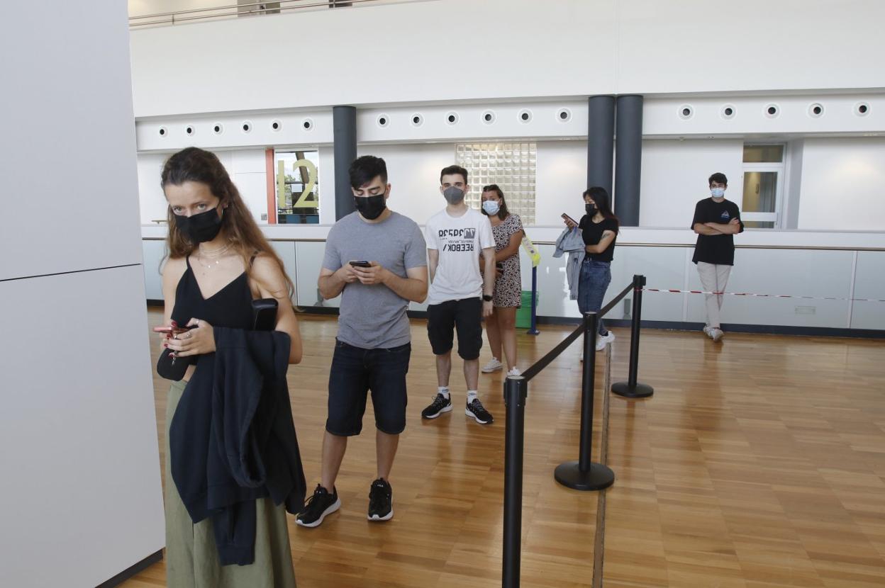 Varios jóvenes hacen cola para recibir la dosis en uno de los cubos de vacunación del HUCA. 