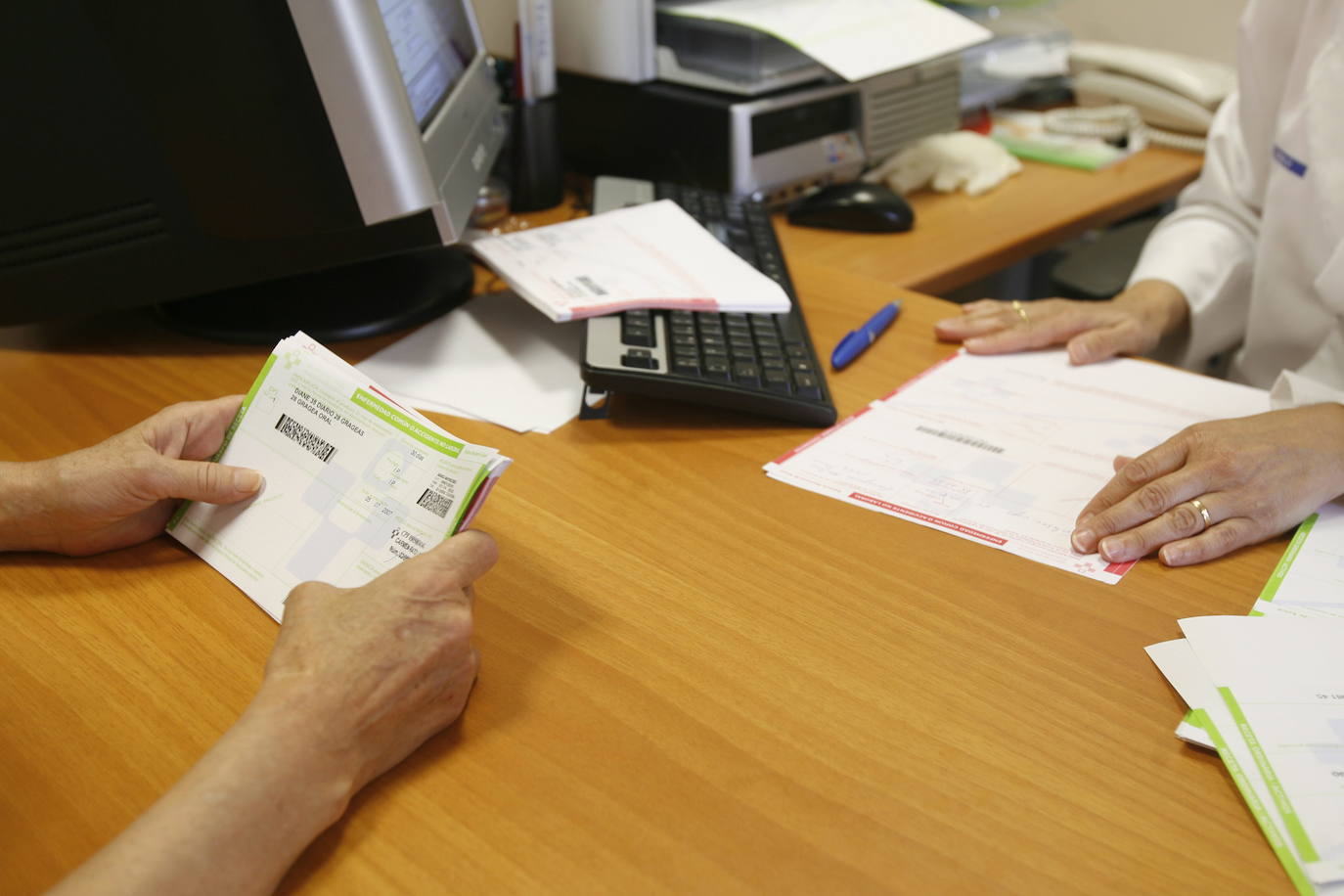 Un médico hace entrega de unas recetas médicas a un paciente.