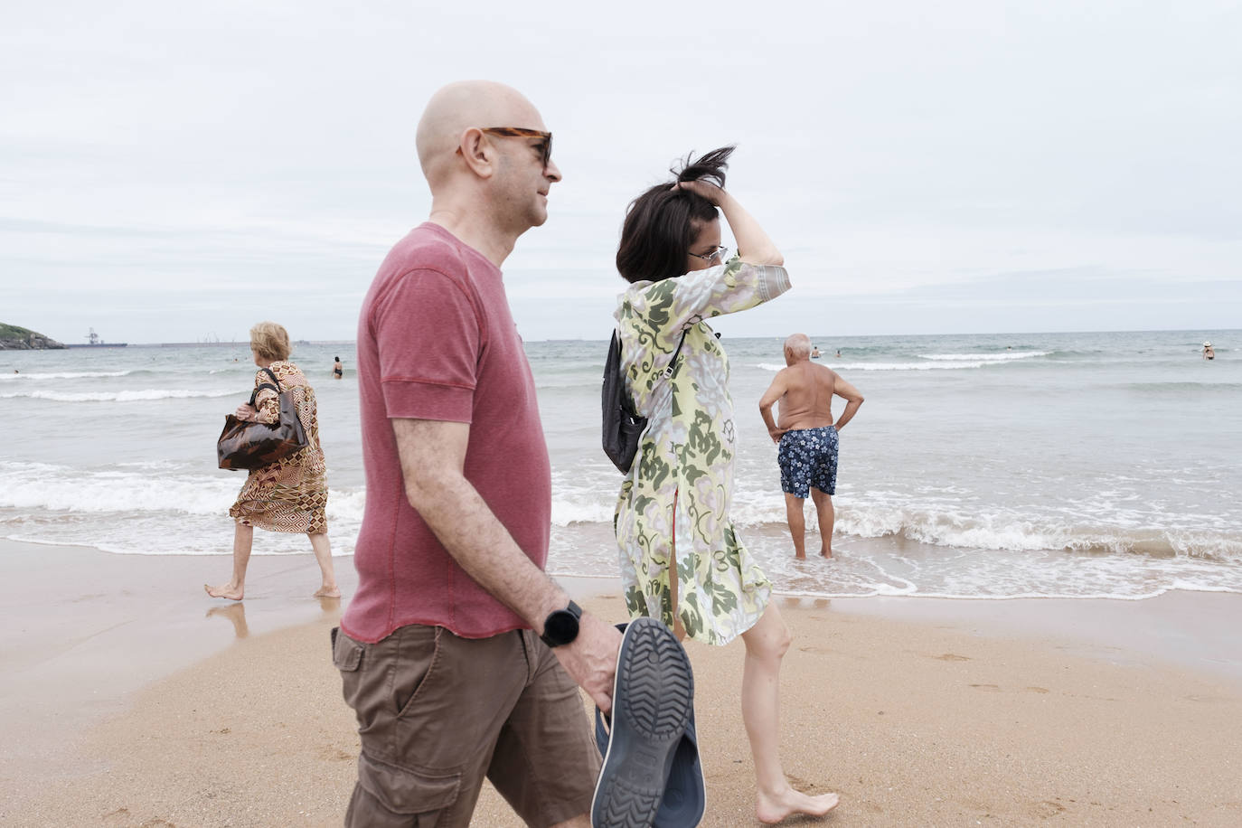 Está siendo un verano atípico en la costa asturiana, pero el mal tiempo no ha impedido que los bañistas se lancen a la playa de San Lorenzo con ganas de disfrutar del día. Algunos pasean, otros leen con la ropa puesta y los más valientes se atreven a darse un chapuzón. Cualquier plan es preferible a quedarse en casa.