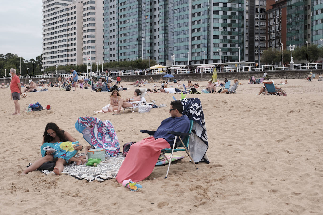 Está siendo un verano atípico en la costa asturiana, pero el mal tiempo no ha impedido que los bañistas se lancen a la playa de San Lorenzo con ganas de disfrutar del día. Algunos pasean, otros leen con la ropa puesta y los más valientes se atreven a darse un chapuzón. Cualquier plan es preferible a quedarse en casa.