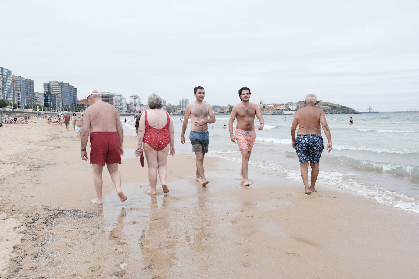 Está siendo un verano atípico en la costa asturiana, pero el mal tiempo no ha impedido que los bañistas se lancen a la playa de San Lorenzo con ganas de disfrutar del día. Algunos pasean, otros leen con la ropa puesta y los más valientes se atreven a darse un chapuzón. Cualquier plan es preferible a quedarse en casa.