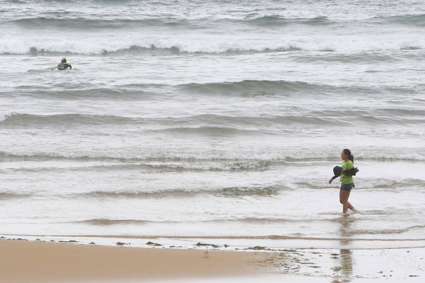 Está siendo un verano atípico en la costa asturiana, pero el mal tiempo no ha impedido que los bañistas se lancen a la playa de San Lorenzo con ganas de disfrutar del día. Algunos pasean, otros leen con la ropa puesta y los más valientes se atreven a darse un chapuzón. Cualquier plan es preferible a quedarse en casa.