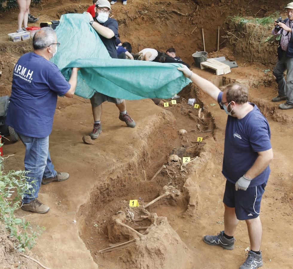 Trabajo. Los voluntarios levantan una lona para descubrir el hallazgo.