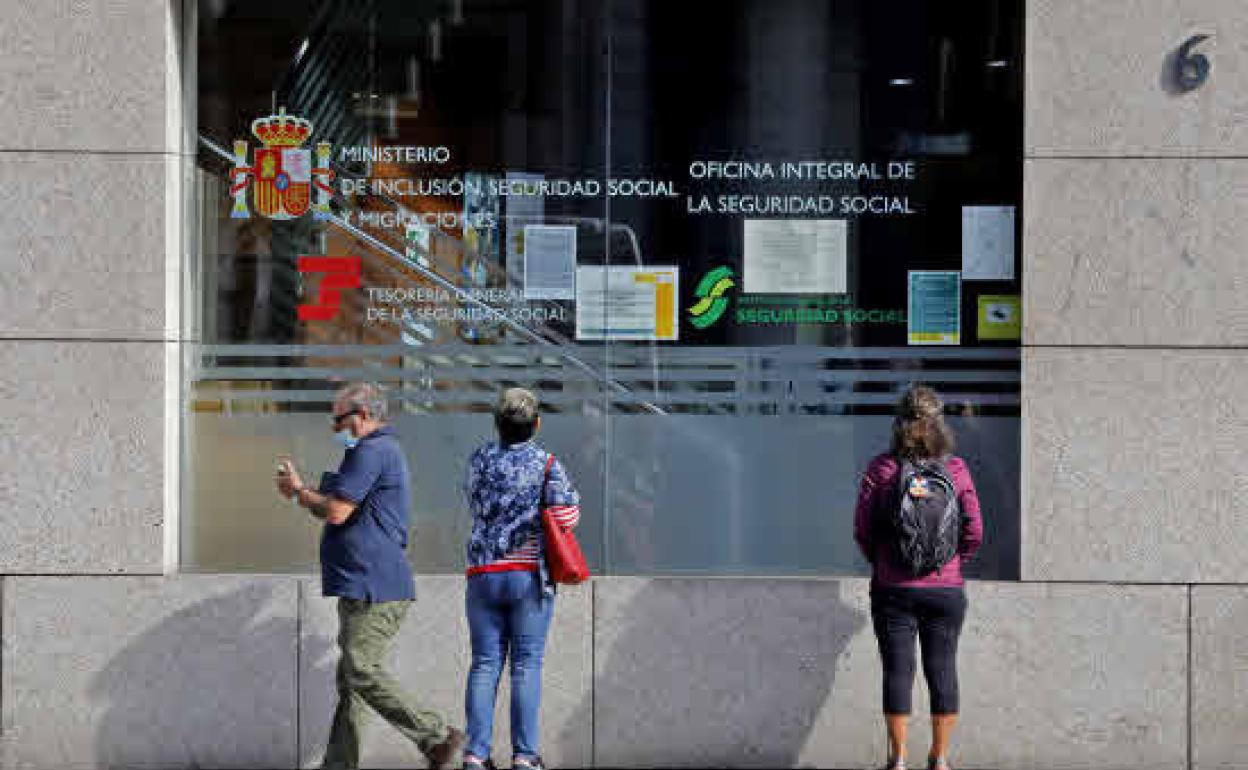 Varios ciudadanos ante las oficinas de la Seguridad Social.