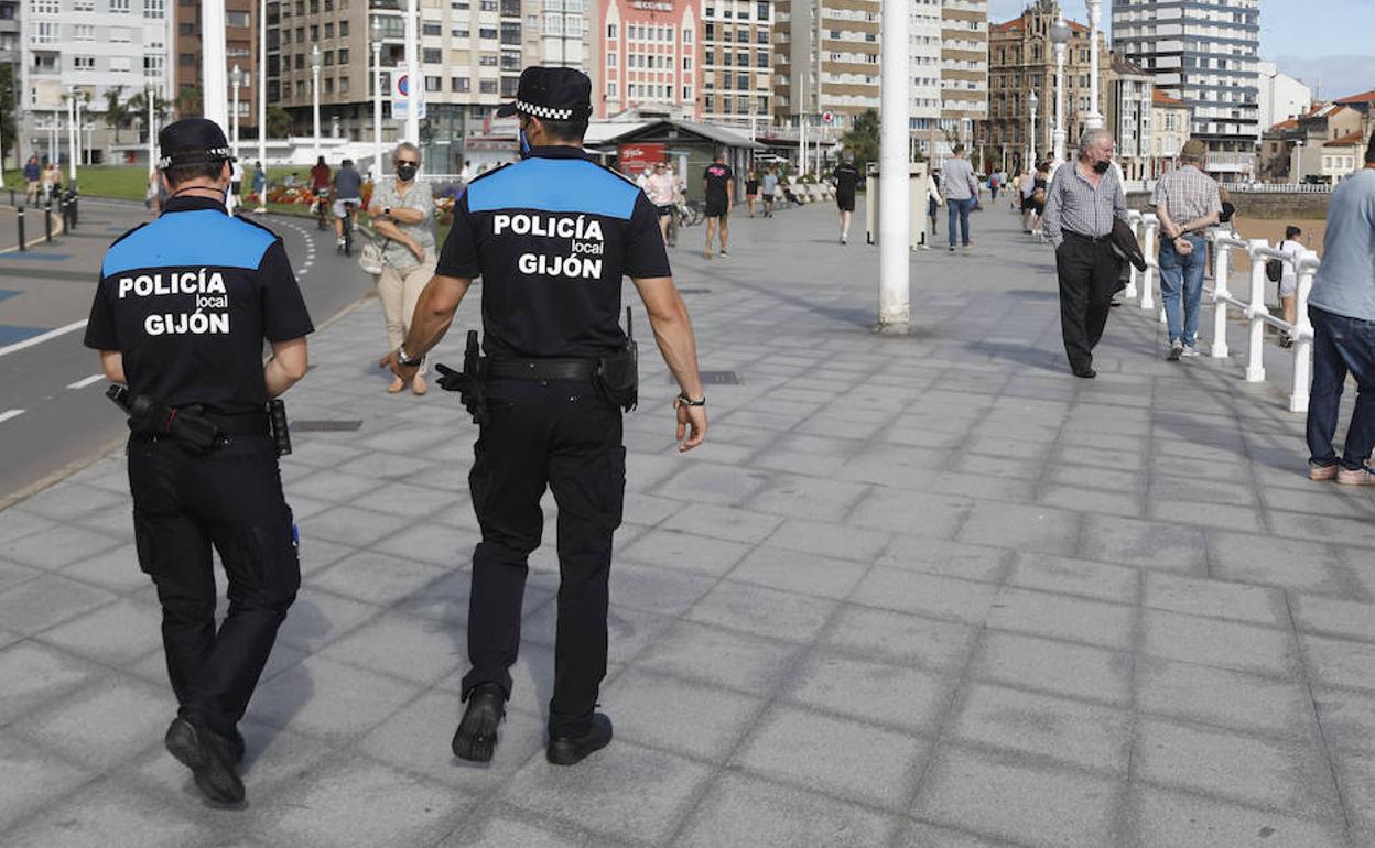 Dos policías locales patrullan por el muro de San Lorenzo de Gijón.