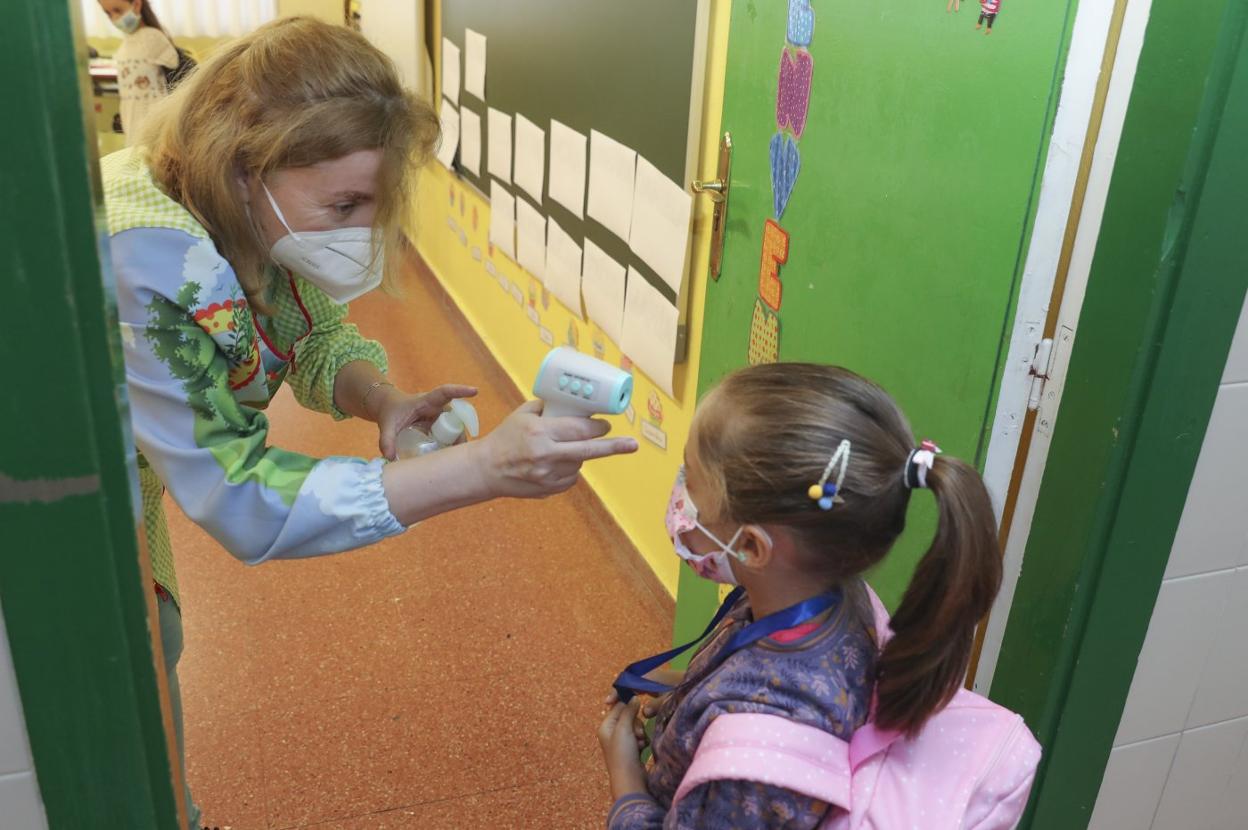 Una docente toma la temperatura a una niña en el inicio del curso escolar 2020-2021. 