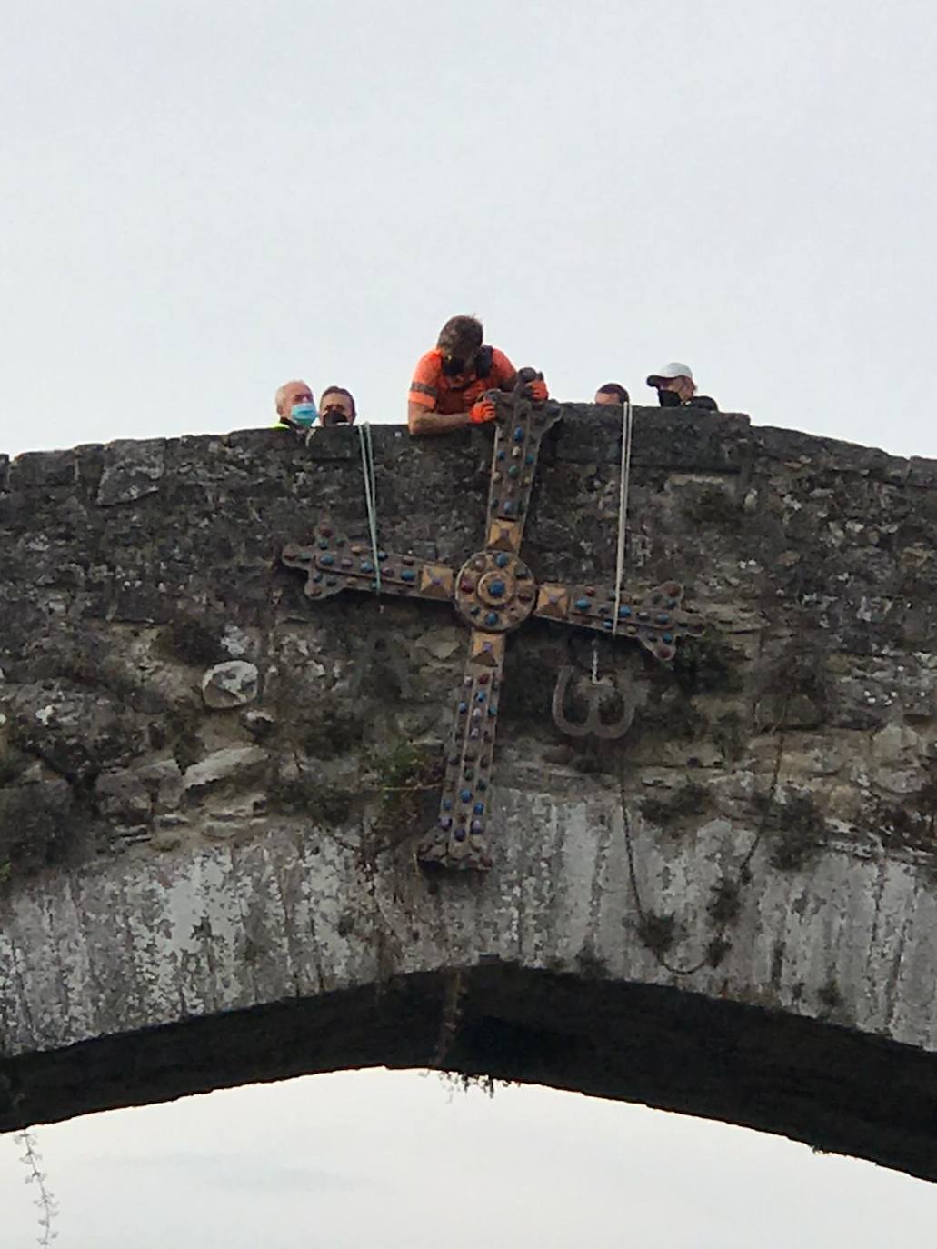 A primera hora de la mañana, operarios del Ayuntamiento procedieron a colocar y asegurar la Cruz de la Victoria del Puente Romano de Cangas de Onís