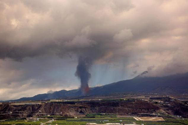 Una columna de humo y materiales piroclásticos es arrojada por el volcán Cumbre Vieja detrás de las plantaciones de plátanos.