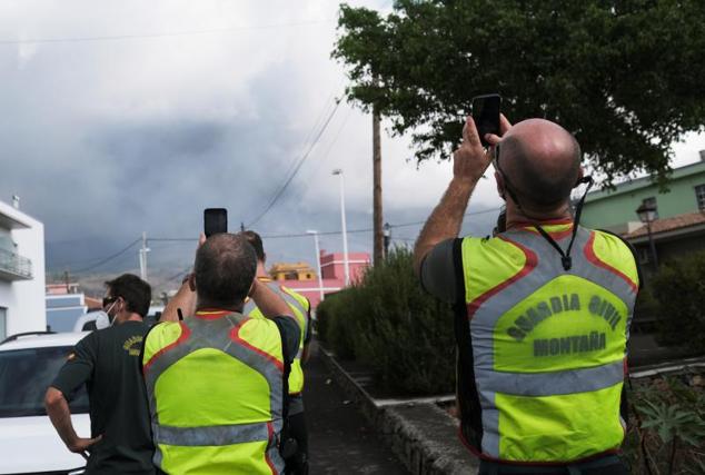 Miembros de la Guardia Civil toman fotografías del humo que se eleva tras la erupción del volcán.