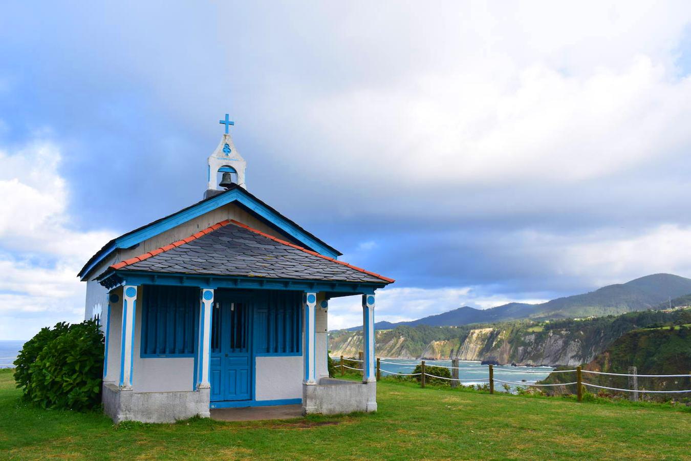 En el pueblo de Cadavedo y en pleno concejo de Valdés, es donde esta vez te acercamos y donde se encuentra el mirador de La Regalina, uno de esos lugares especiales que pueden encontrarse a ras de la costa asturiana y desde el que podrás disfrutar de una de las mejores vistas del occidente asturiano y del litoral. Un estupendo balcón en el que los pastos verdes tiñen de color un paisaje único y en el que la gran protagonista es una pequeña ermita de 1931 y dos hórreos, los cuales se encargan de presidir los acantilados de más de 70 metros sobre los que se ubica este mirador. Una panorámica única que nos acerca a ese Paisaje Protegido de la Costa Occidental Asturiana en el que se fusionan a la perfección mar y montaña, regalándonos unas vistas inigualables de la Playa de Cadavedo y Ribón y al arenal de Churín.