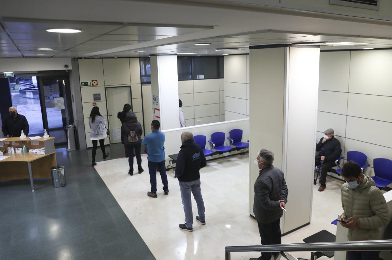 Varios usuarios hacen cola en el centro de salud de Zarracina, en Gijón. 