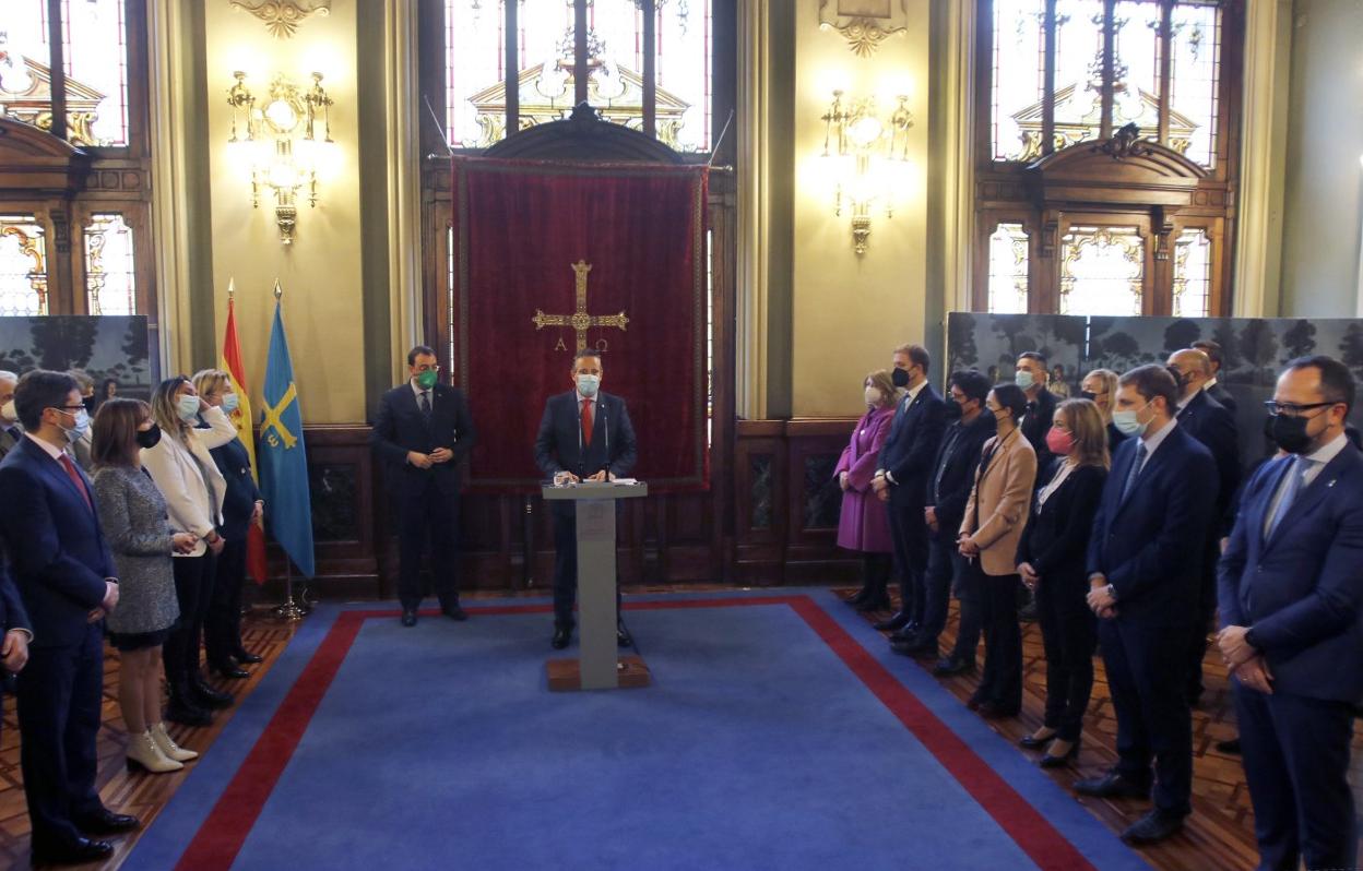 Marcelino Marcos pronuncia su discurso institucional en el salón Europa del Parlamento asturiano. Tras él, el presidente del Principado, Adrián Barbón. En primer plano, a la izquierda, Ignacio Blanco y Adrián Pumares, junto al resto de portavoces políticos. 