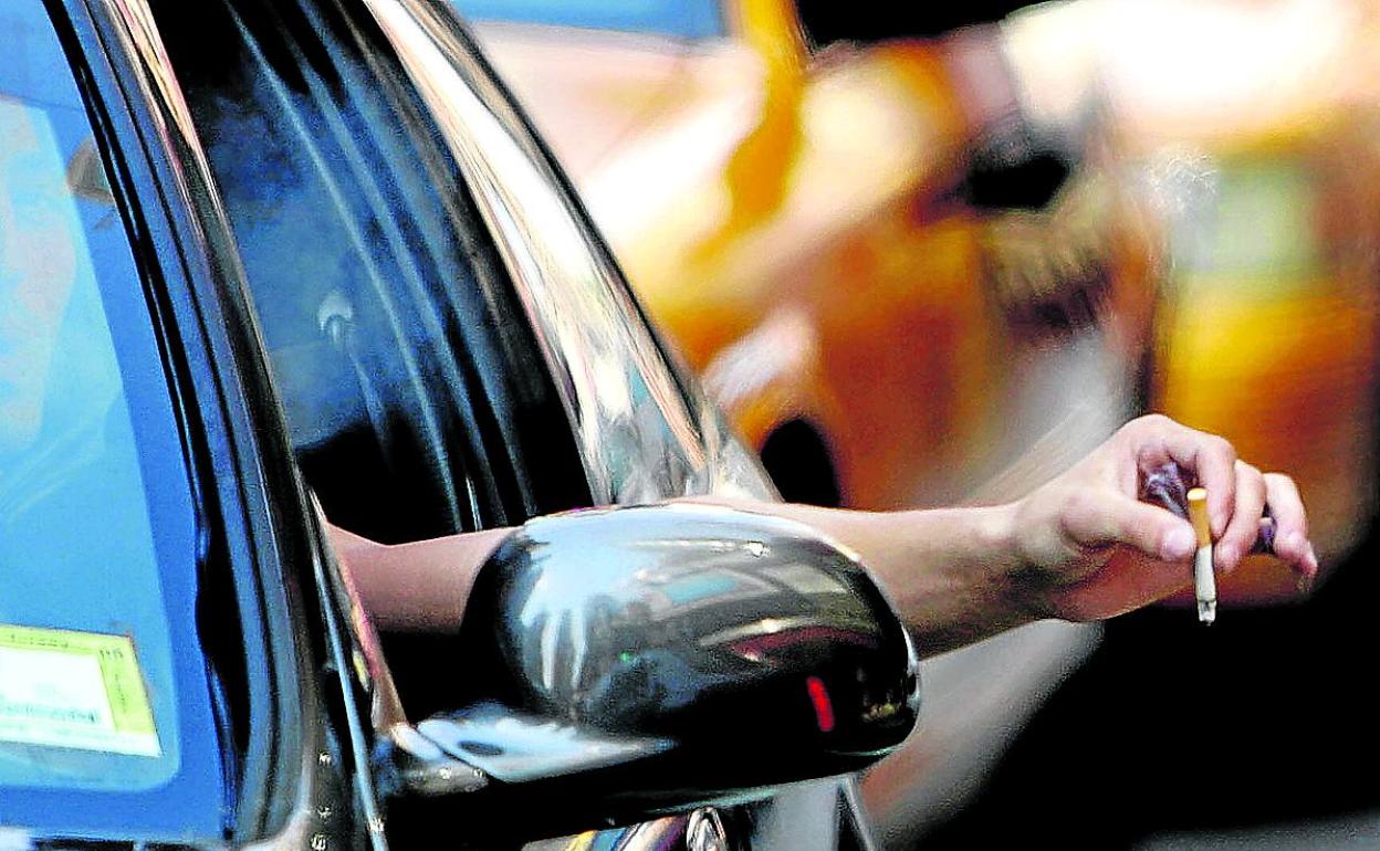 n conductor se fuma un cigarrillo mientras aguarda en un semáforo. 