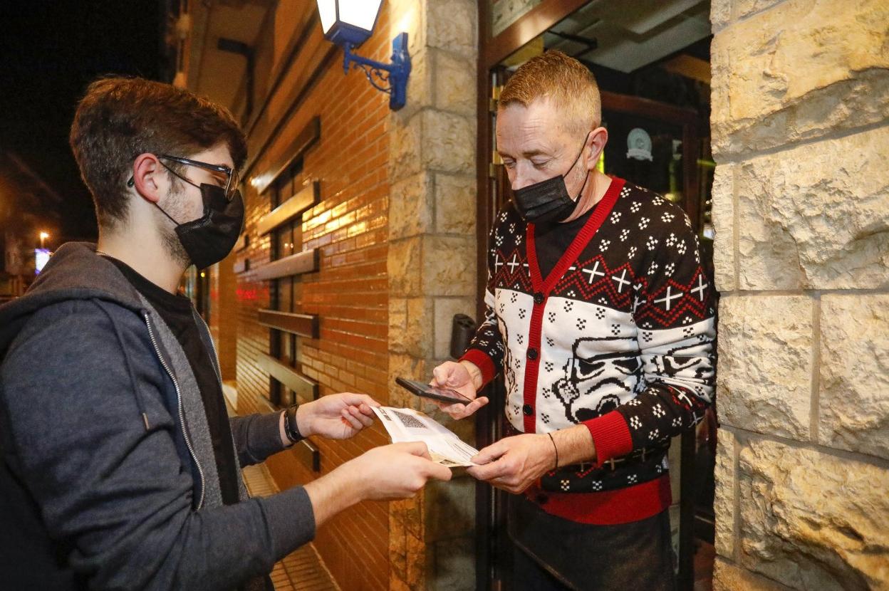 Un hostelero comprueba el pasaporte covid de un cliente de la cervecería Donald Castle, en Gijón. 