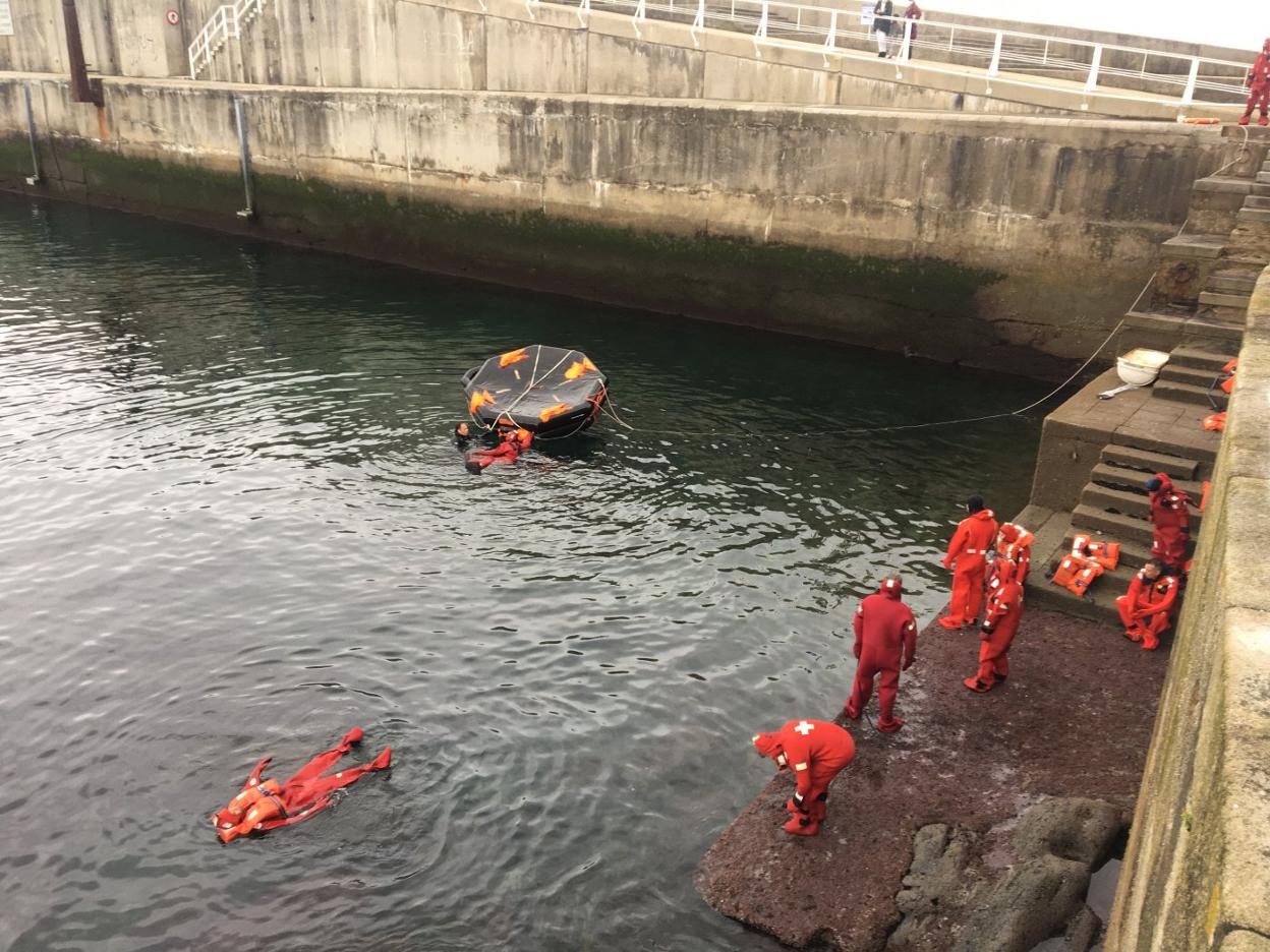 El alumnado del curso aprende a voltear la balsa durante una de sus prácticas en el muelle de Luarca. 