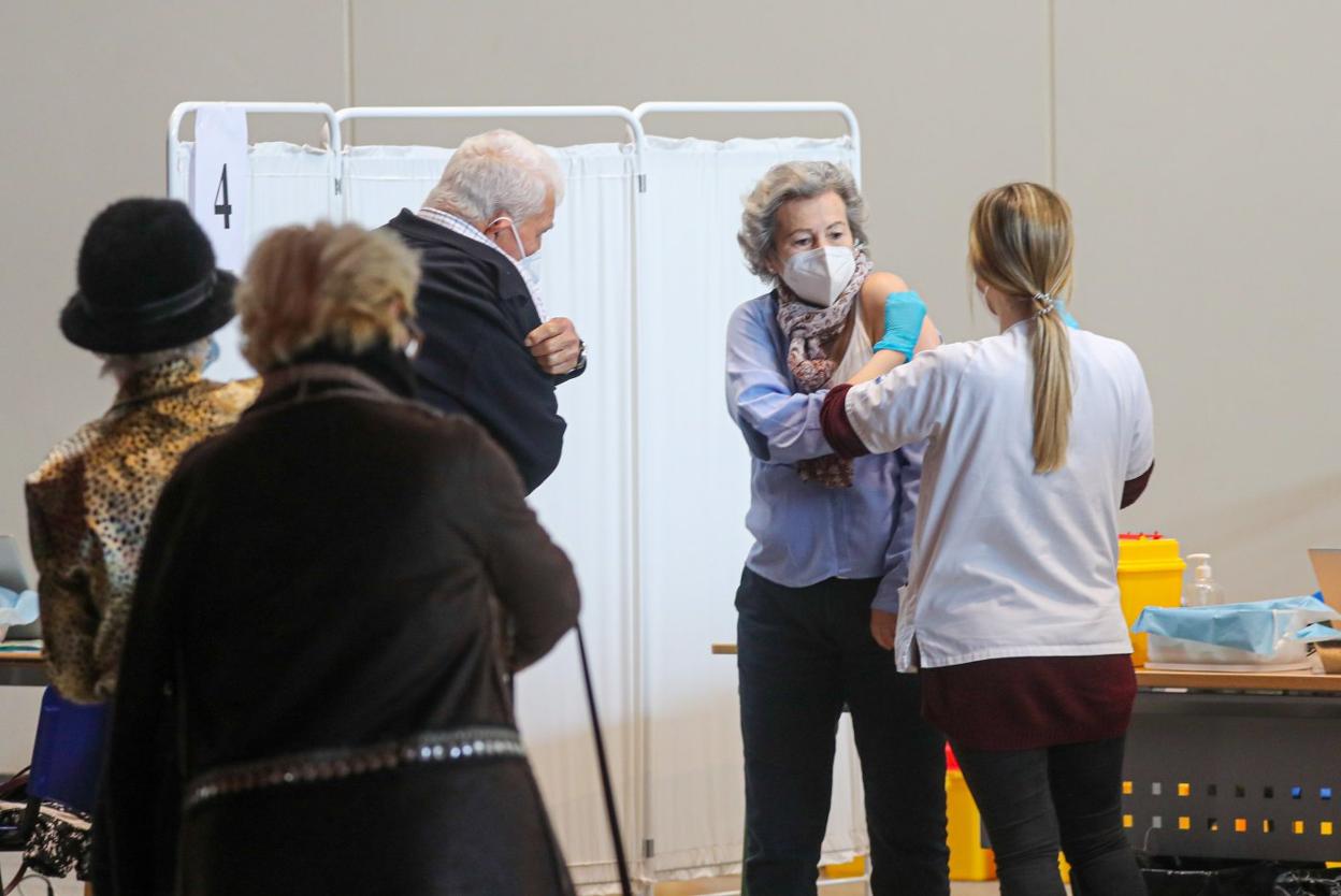 Unos usarios recibe la tercera dosis de la vacuna en el Palacio de Deportes de Gijón . 