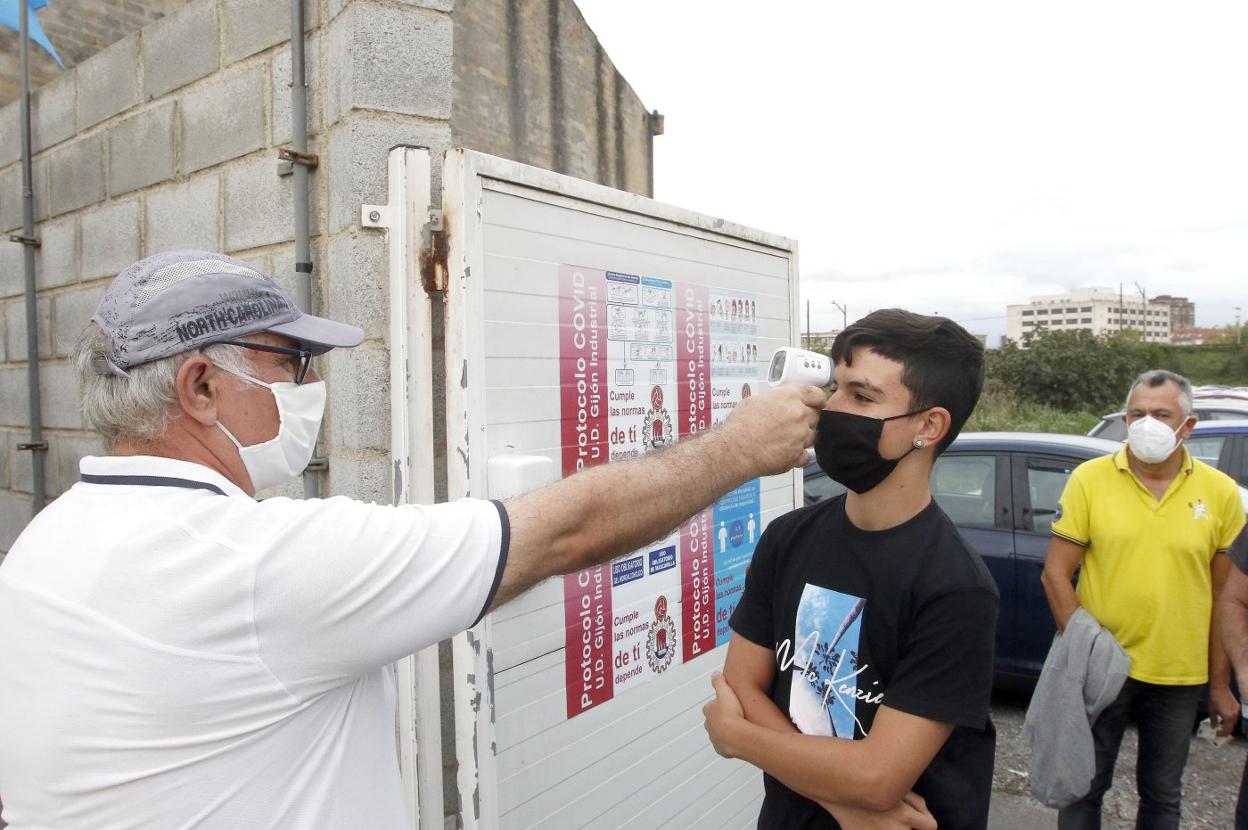 Un empleado toma la temperatura a un joven antes de acceder a un estadio de fútbol en Gijón. 