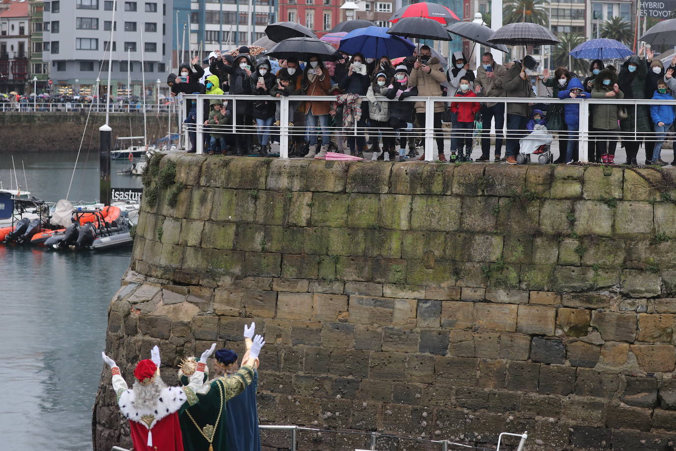 Los Reyes Magos atracaban en el puerto de Gijón bajo la lluvia sobre las 11 de la mañana mientras centenares de niños coreaban lo nombres de Sus Majestades.