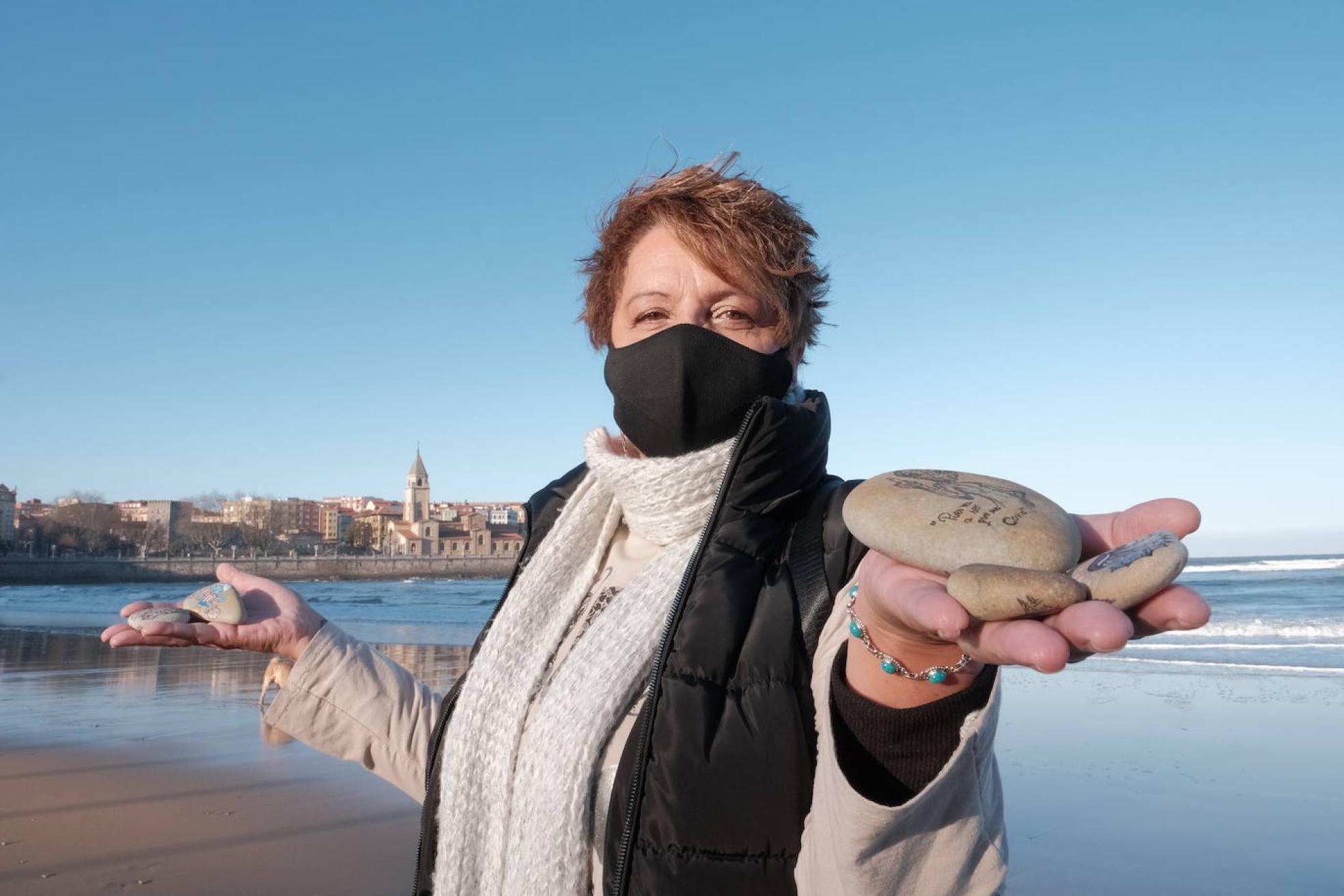 Denise Álvarez sostiene algunas de sus piedras viajeras en la playa de San Lorenzo. 