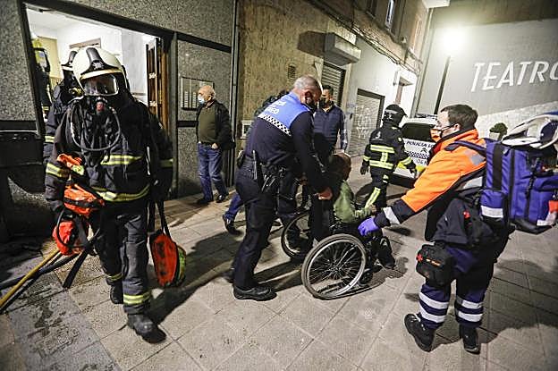 La Policía Local ayuda a evacuar a uno de los vecinos heridos en el incendio. 