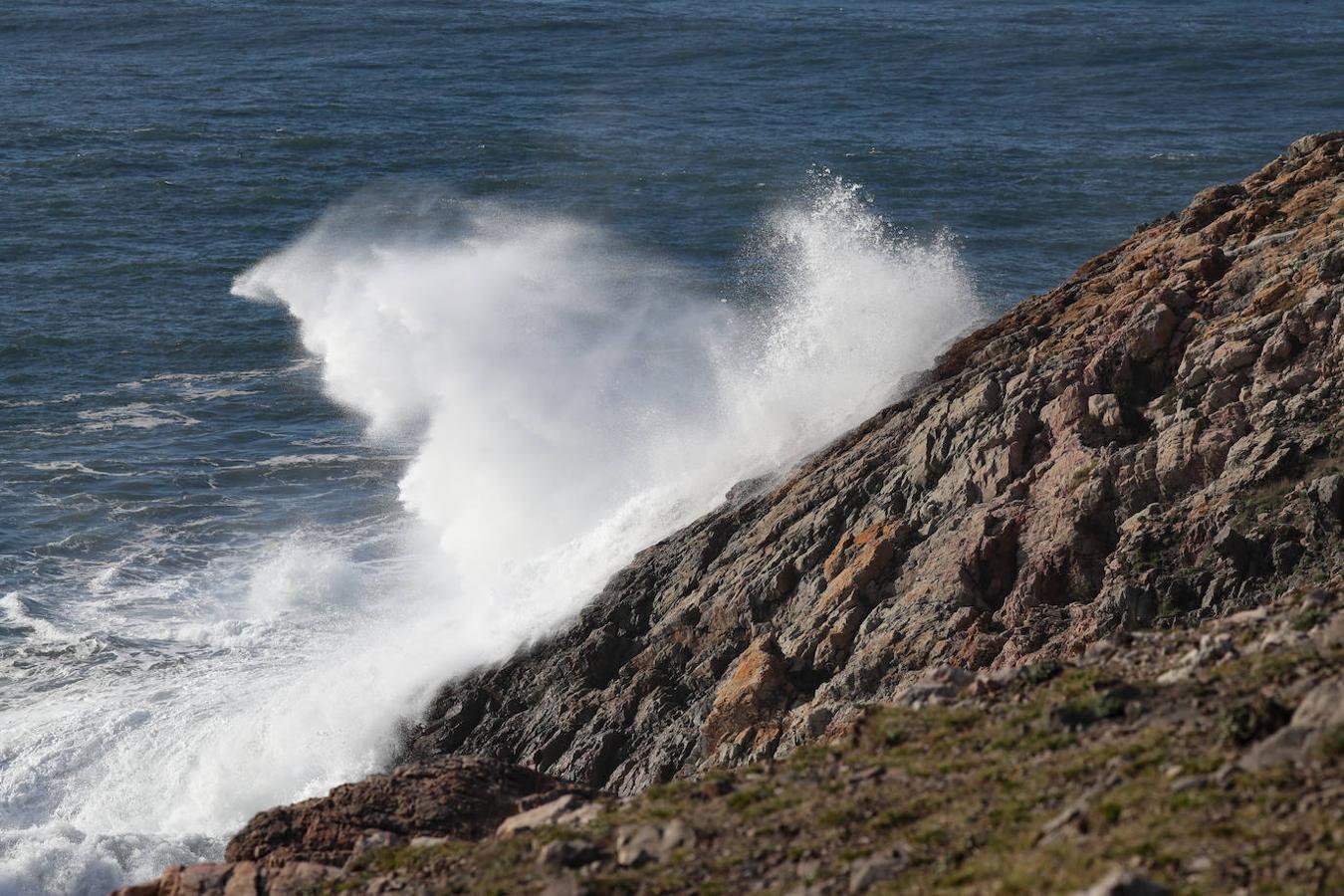 El faro de San Juan de Nieva estuvo rodeado de un fuerte oleaje durante la jornada de este jueves, en Avilés.