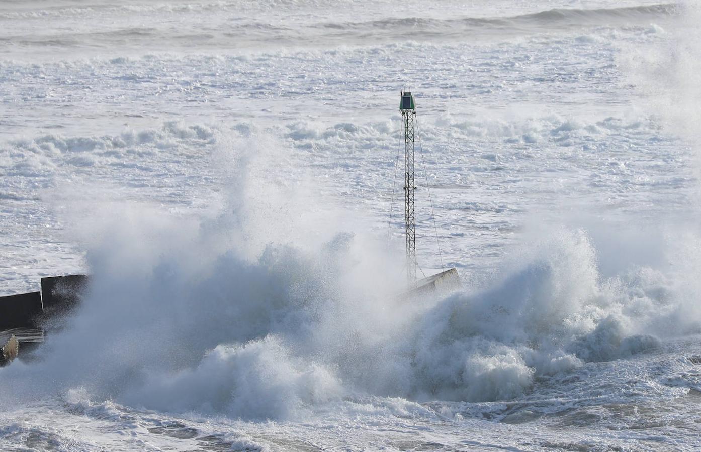 El faro de San Juan de Nieva estuvo rodeado de un fuerte oleaje durante la jornada de este jueves, en Avilés.