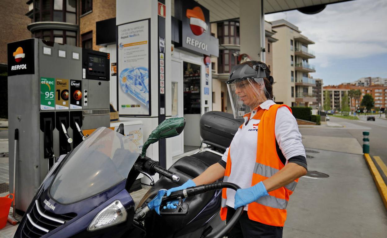 Una operaria de una gasolinera de Gijón, llenando el depósito de una moto