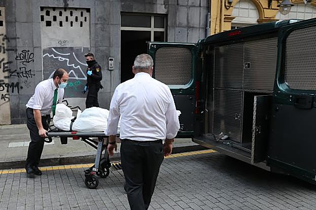 Los servicios funerarios trasladan el cadáver al furgón fúnebre. 