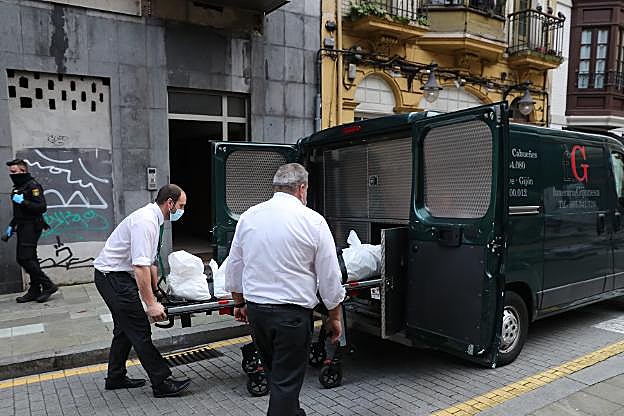 Los servicios funerarios trasladan el cadáver. 